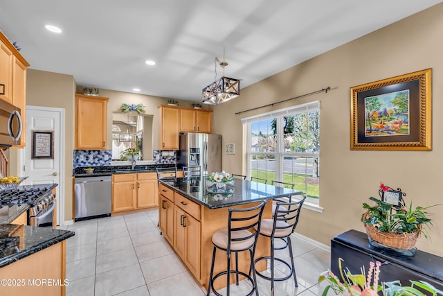 kitchen featuring appliances with stainless steel finishes, light brown cabinets, light tile patterned floors, a kitchen breakfast bar, and backsplash