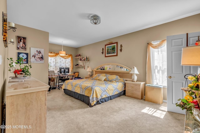 bedroom featuring light carpet and a desk