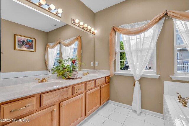 bathroom with double vanity, tile patterned floors, baseboards, and tiled tub