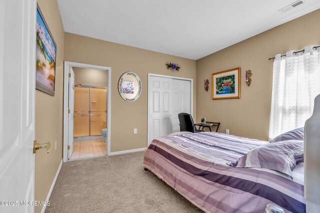 carpeted bedroom featuring baseboards, a closet, and ensuite bath
