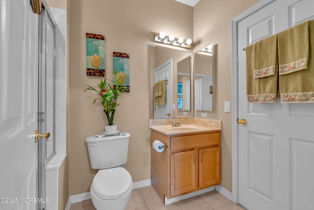 bathroom with tile patterned flooring, baseboards, vanity, and toilet