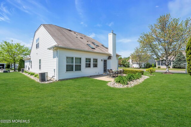 rear view of house featuring a chimney, a yard, a patio area, cooling unit, and a shingled roof