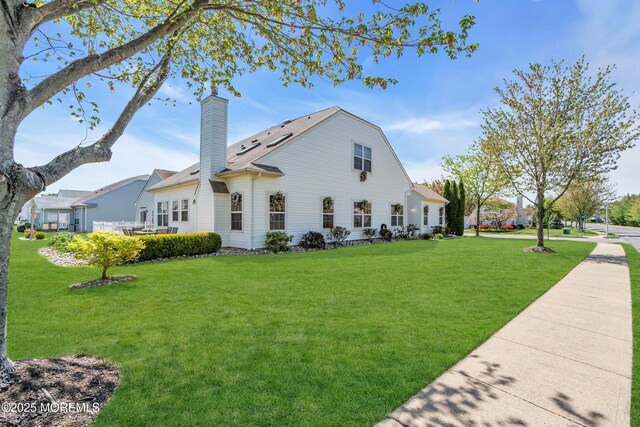 view of side of home featuring a chimney and a yard