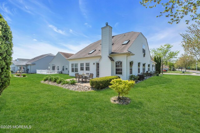 rear view of property featuring a patio area, a lawn, a chimney, and a shingled roof