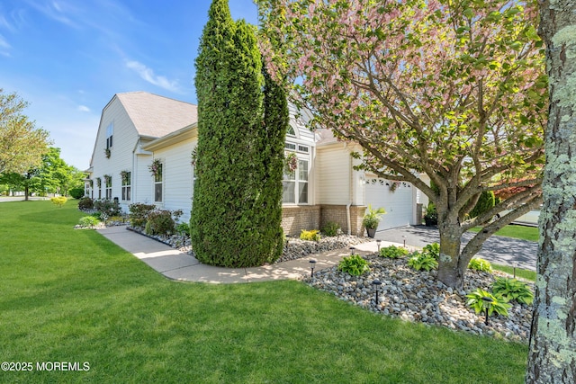 view of side of property featuring a lawn, concrete driveway, and brick siding