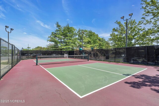 view of tennis court with community basketball court and fence