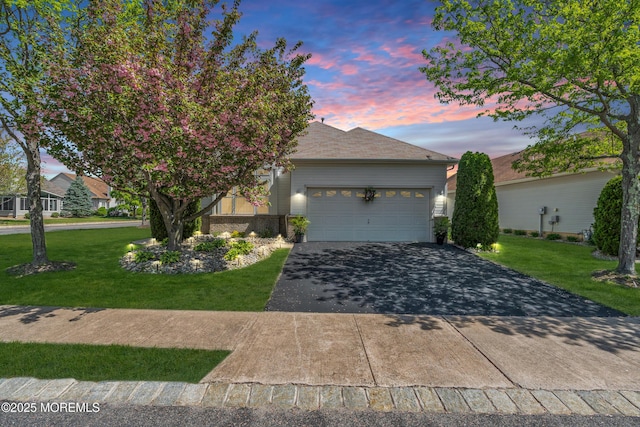 ranch-style home with driveway, a yard, a garage, and brick siding