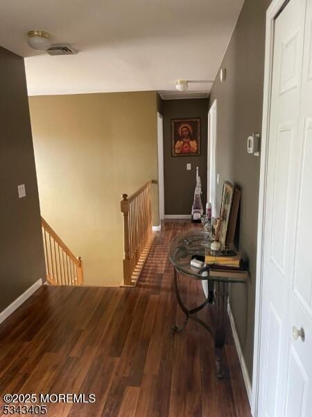 hall featuring wood finished floors, visible vents, an upstairs landing, and baseboards