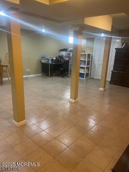 finished below grade area with baseboards and tile patterned floors
