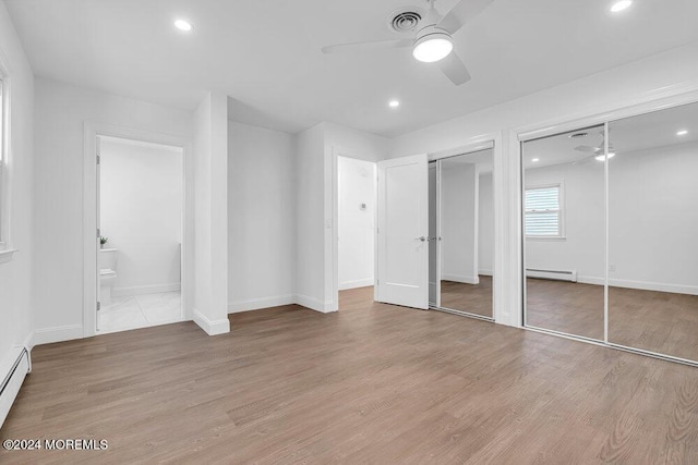 unfurnished bedroom with recessed lighting, a baseboard radiator, two closets, and light wood finished floors