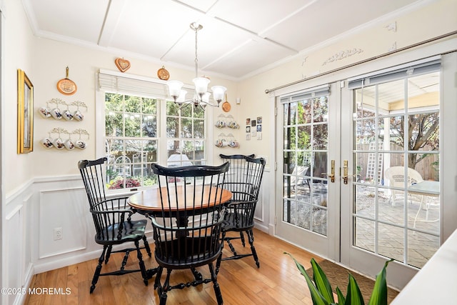 dining room featuring an inviting chandelier, crown molding, french doors, and light wood-type flooring
