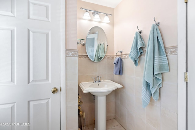 bathroom with a sink, tile walls, and wainscoting