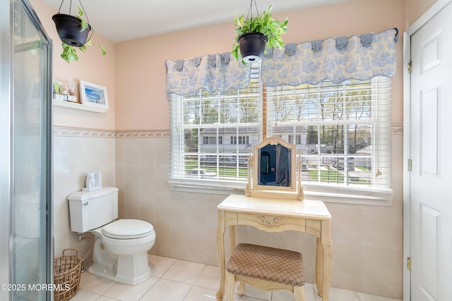 bathroom with plenty of natural light, tile patterned flooring, toilet, and tile walls