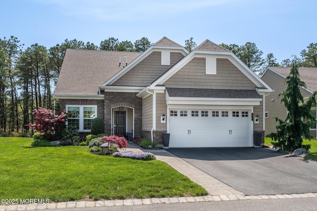 craftsman-style home featuring a garage, a front lawn, aphalt driveway, stone siding, and roof with shingles