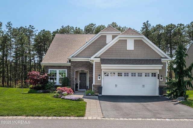 craftsman-style house with a front yard, stone siding, roof with shingles, an attached garage, and driveway