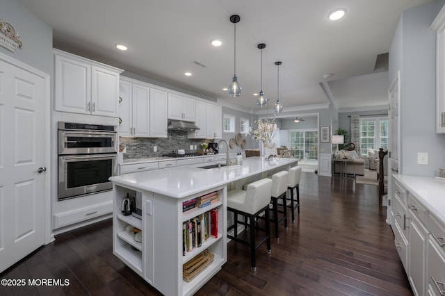 kitchen featuring open shelves, gas cooktop, stainless steel double oven, a sink, and white cabinetry
