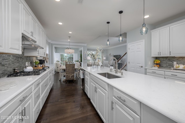 kitchen featuring decorative backsplash, stainless steel gas cooktop, under cabinet range hood, white cabinets, and a sink