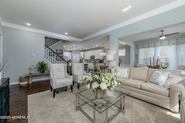 living area with crown molding, stairs, wood finished floors, baseboards, and ceiling fan