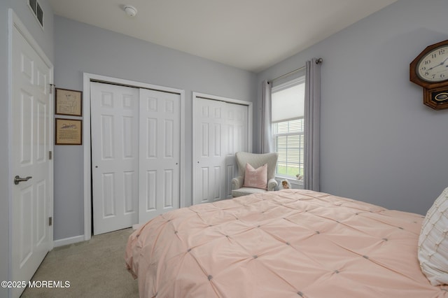 bedroom with carpet floors, multiple closets, baseboards, and visible vents