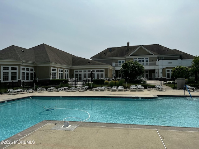 pool with a patio area and fence