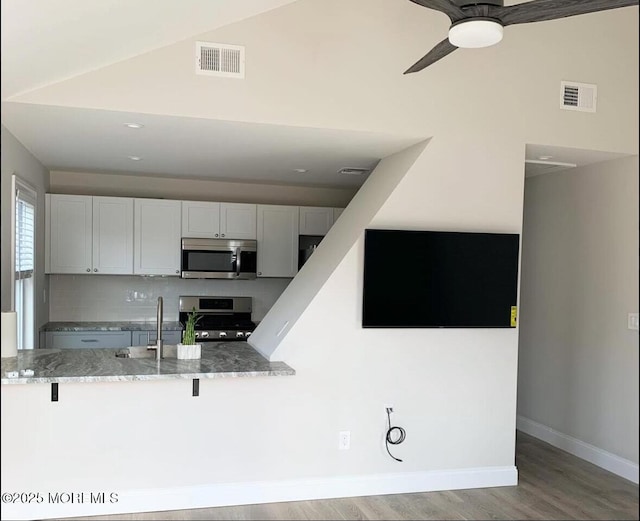 kitchen featuring visible vents, light wood-style flooring, appliances with stainless steel finishes, and light stone countertops