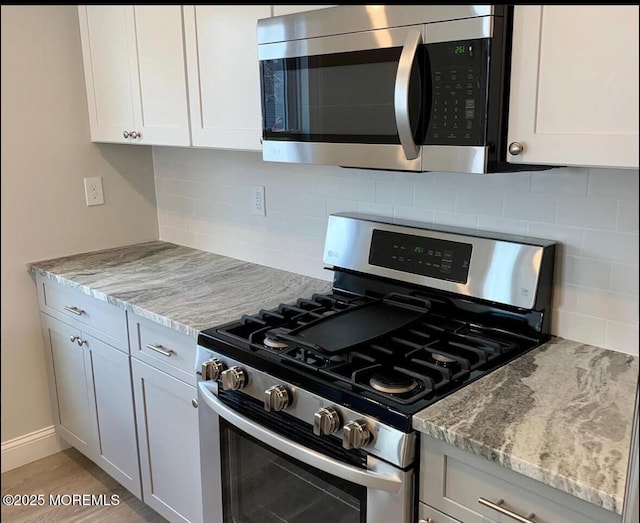 kitchen featuring appliances with stainless steel finishes, decorative backsplash, light stone countertops, and white cabinets