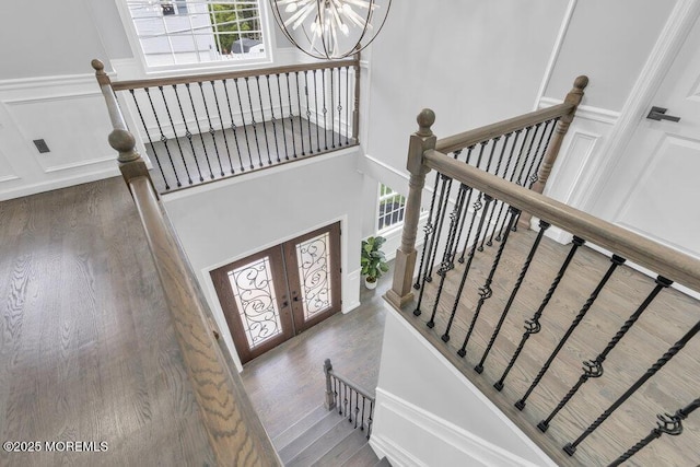 staircase with an inviting chandelier, a wealth of natural light, french doors, and a towering ceiling