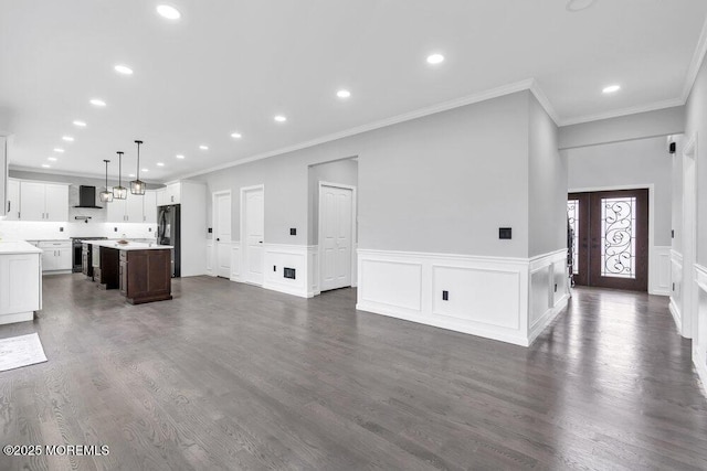 unfurnished living room with recessed lighting, ornamental molding, and a wainscoted wall