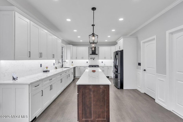 kitchen featuring crown molding, freestanding refrigerator, tasteful backsplash, a sink, and dishwasher