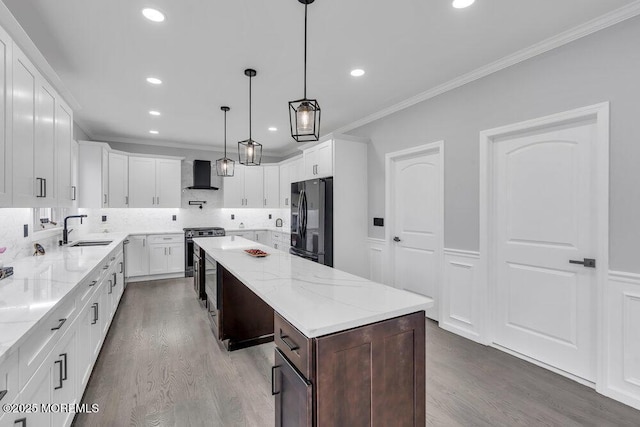 kitchen featuring black fridge with ice dispenser, crown molding, wood finished floors, a center island, and a sink