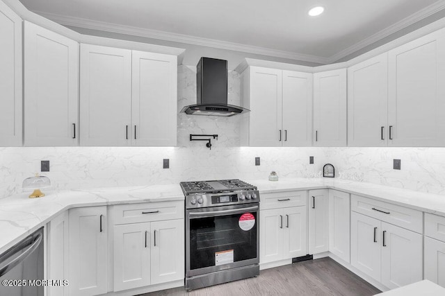 kitchen with wall chimney exhaust hood, tasteful backsplash, white cabinets, and stainless steel appliances