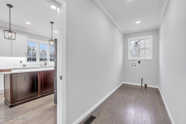 clothes washing area featuring crown molding, visible vents, baseboards, light wood-style floors, and washer hookup