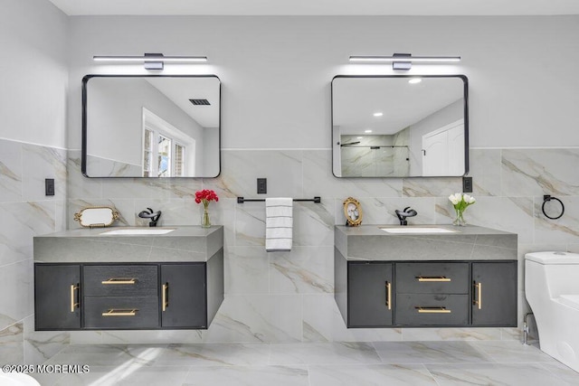 bathroom with tile walls, two vanities, and a sink