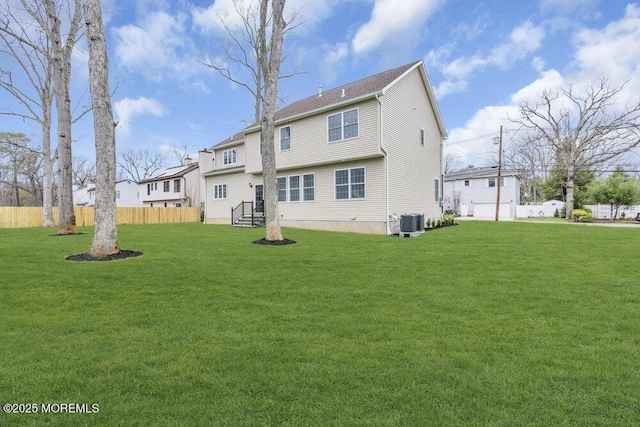 back of house with fence, central AC unit, and a lawn