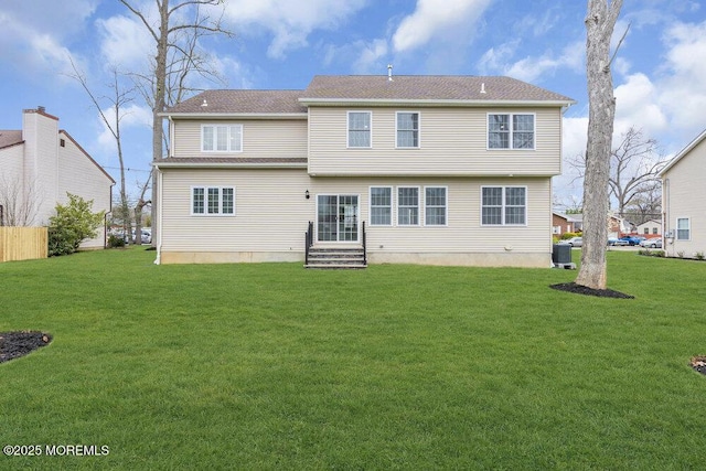 rear view of house with entry steps, a yard, and cooling unit