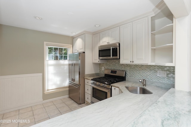 kitchen featuring open shelves, light stone countertops, tasteful backsplash, a sink, and appliances with stainless steel finishes