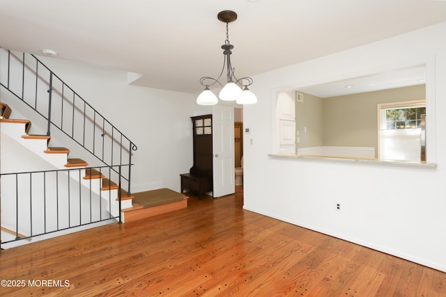 interior space featuring baseboards, wood finished floors, visible vents, and stairway