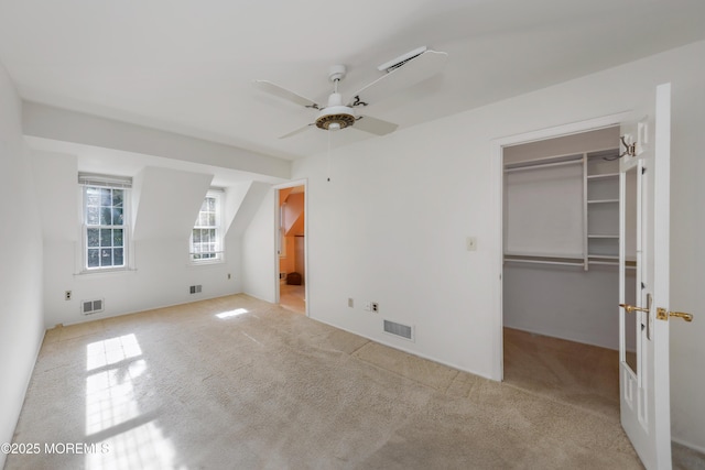 unfurnished bedroom featuring a walk in closet, carpet, and visible vents