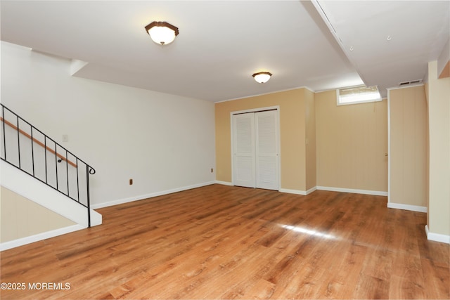 basement with baseboards, visible vents, stairway, and light wood-style floors