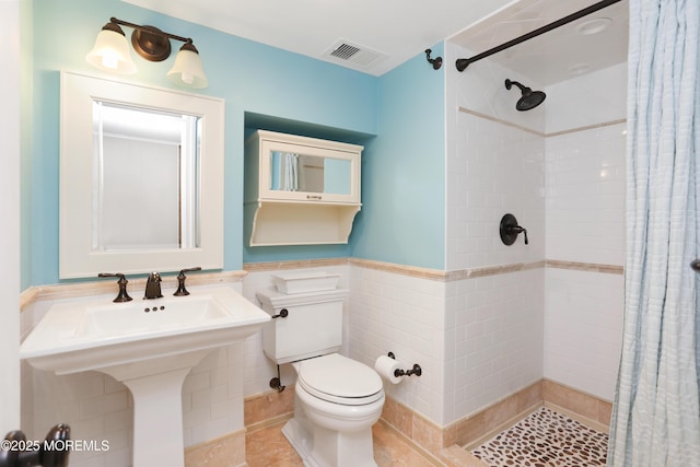 full bath with visible vents, a stall shower, toilet, and tile walls