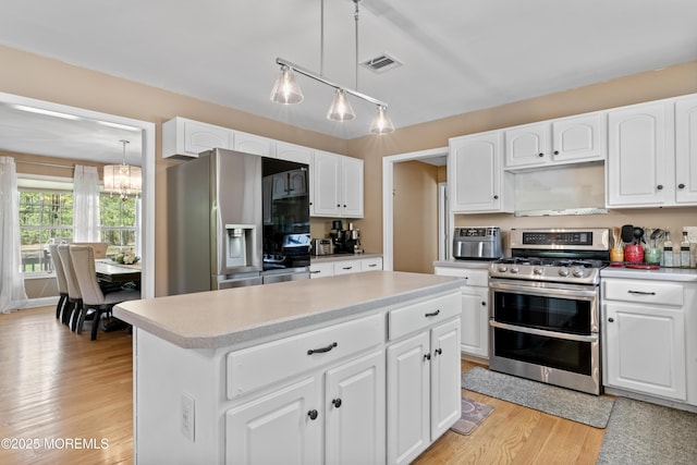 649 Toms River Rd, Jackson, NJ 08527 - kitchen with appliances with stainless steel finishes, a center island, light wood finished floors, a chandelier, and decorative light fixtures