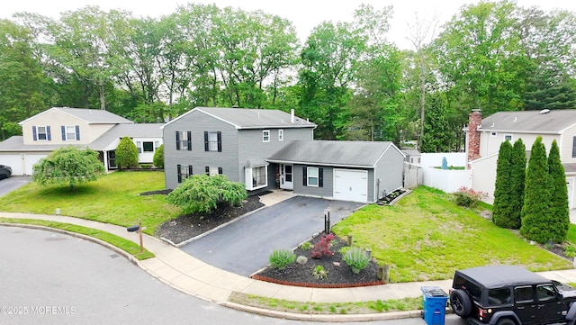 traditional-style house featuring a garage, driveway, and view of scattered trees