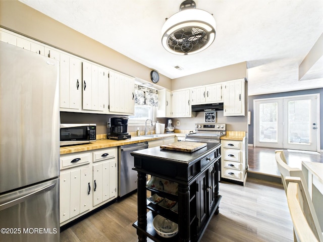 kitchen with appliances with stainless steel finishes, under cabinet range hood, dark wood finished floors, and white cabinetry