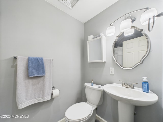 bathroom with baseboards, toilet, a sink, and vaulted ceiling