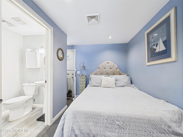 bedroom featuring wood finished floors, ensuite bath, and baseboards