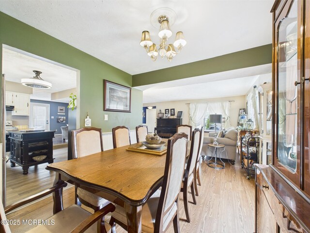 dining room with light wood finished floors and a chandelier
