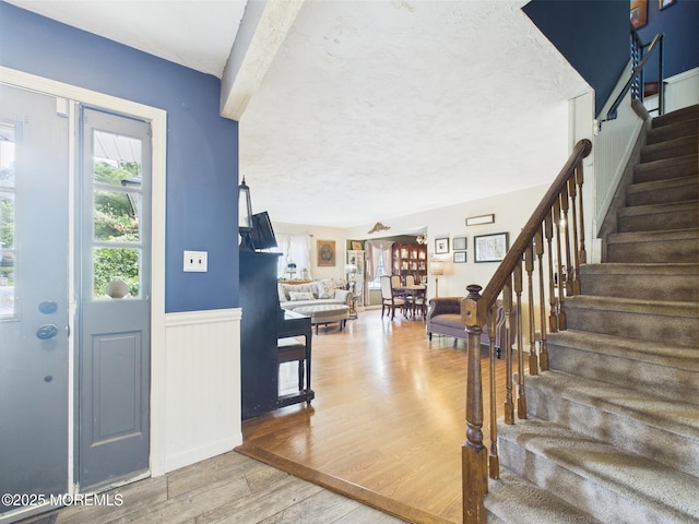 entrance foyer featuring stairway, wood finished floors, wainscoting, and a textured ceiling