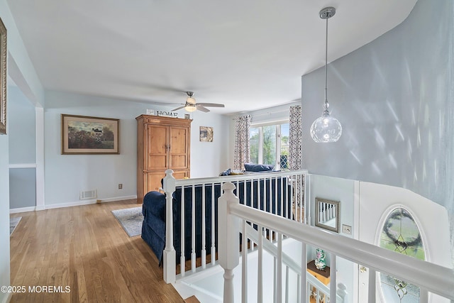 hall with an upstairs landing, wood finished floors, and baseboards