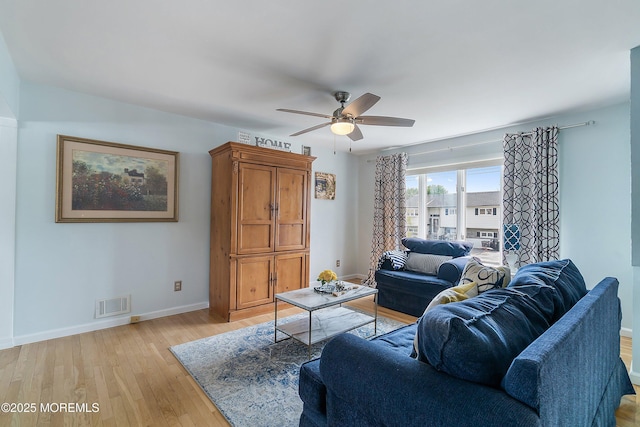 living room with ceiling fan, baseboards, and light wood finished floors