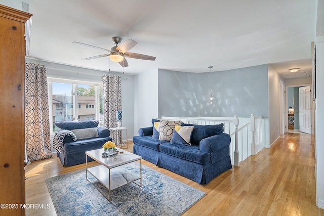living area with a ceiling fan, light wood-style floors, and baseboards